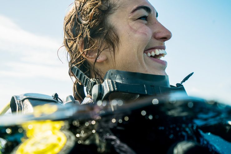 woman smiling while scuba diving at the surface of water