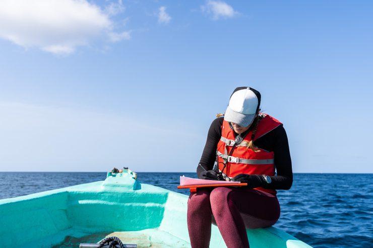 marine biologist writing down data sitting on a boat